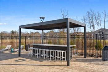 A patio area with a table and chairs under a roof.